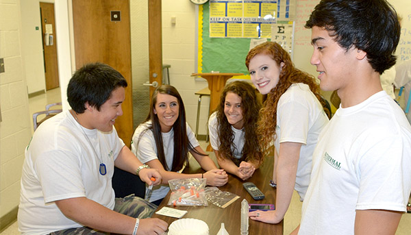 Students standing around table doing a group project