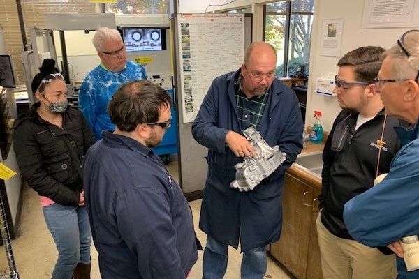 Students standing around looking at die casted parts