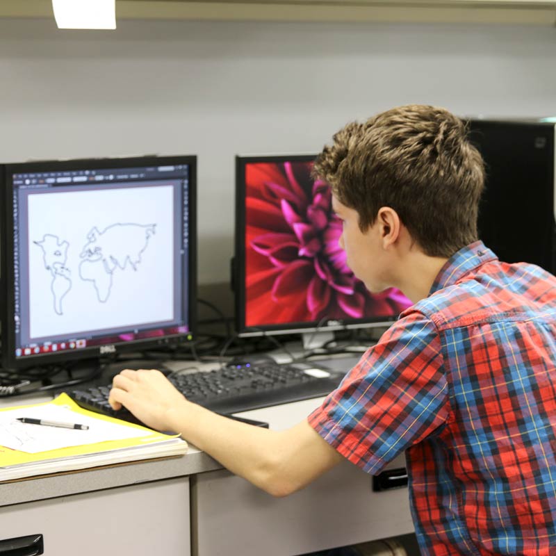 Student drawing outline of countries around the world on the computer