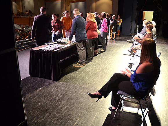 Students inducted in the program are walking across the stage to shake hand with the program coordinators.