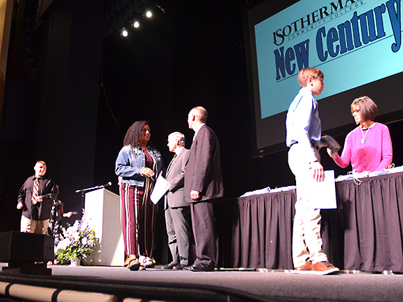 Students walking across the stage to shake hands with the program coordinators.