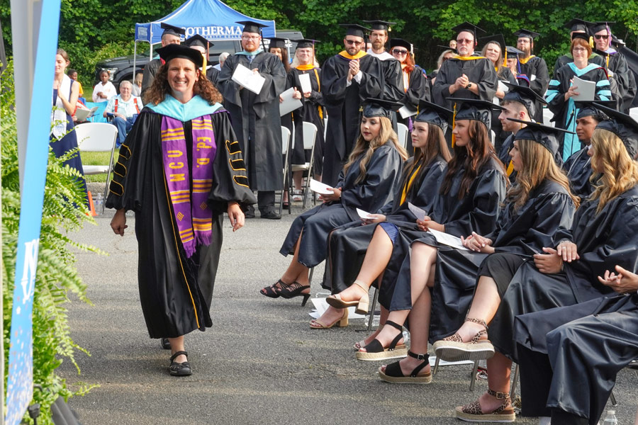 Dr. Alice McCluney walking across aisle to the stage.