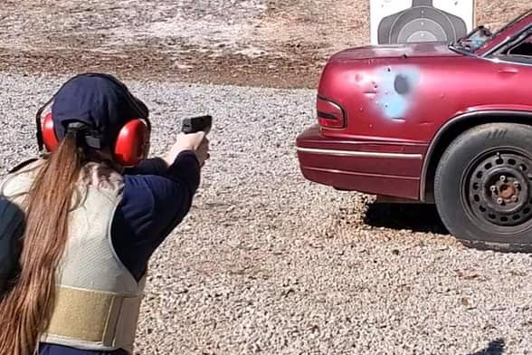 BLET student firing a pistol at a target from behind a car BLET student firing a pistol at a target from behind a car