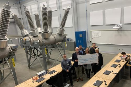 group holding large check in the electronics bay