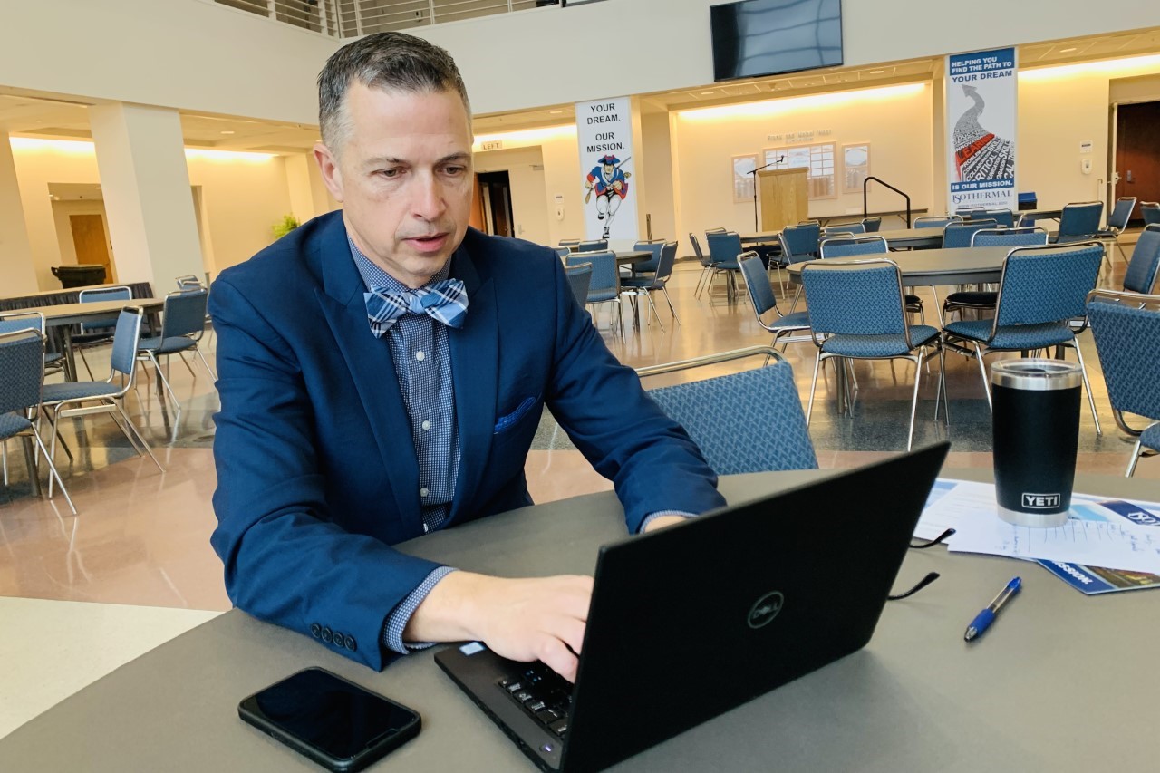 Dr. Harrill working at table in the lobby of the Foundation Performing Arts Center