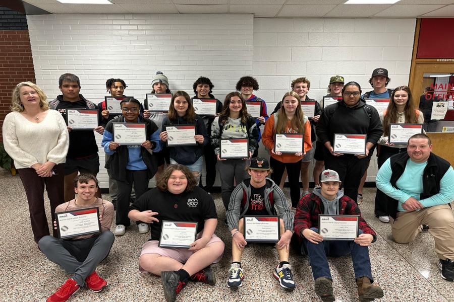 Students in group smiling while showing off their certificates