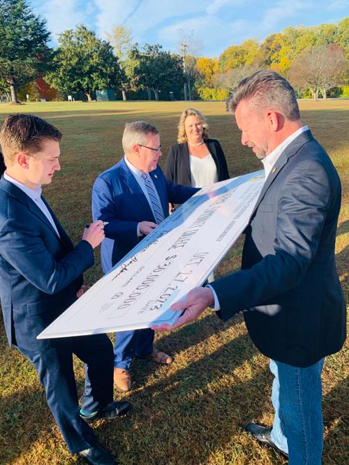 Representative Tim Moore, NC Speaker of the House, signing large oversized check for the presentation ceremony. 