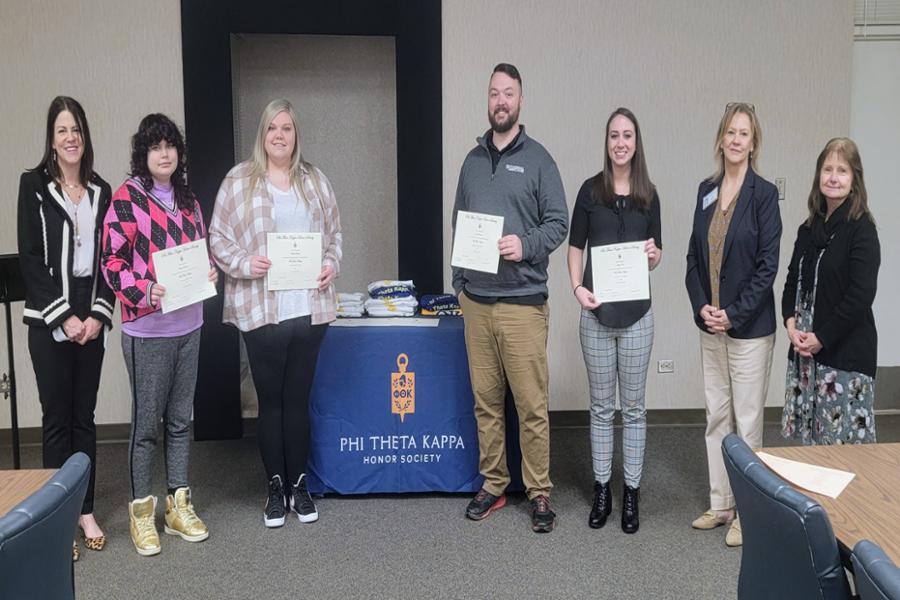 Inductees standing holding their certificates alongside the PTK advisors.