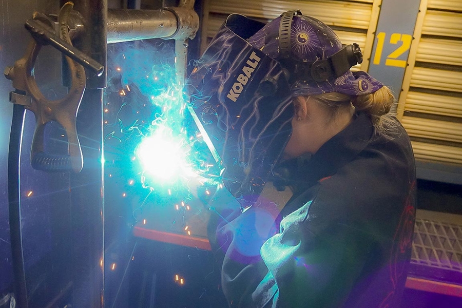Female student welding with sparks flying