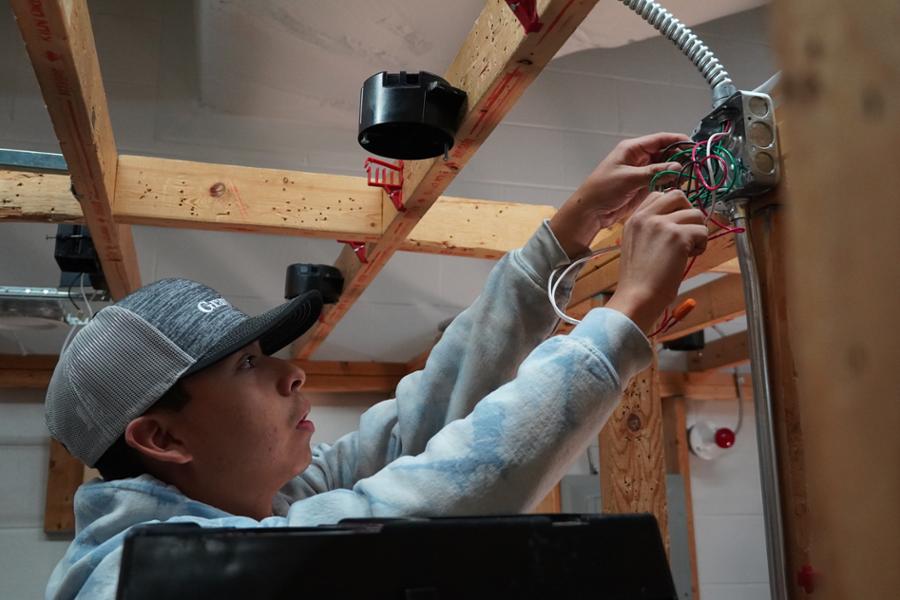 Student wiring an electrical junction box for an overhead light. 